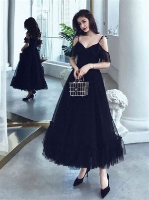 A vintage-inspired black tulle tea-length dress with a sweetheart neckline and cap sleeves, paired with pearl accessories and kitten heels.